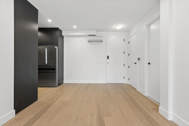 interior space with light wood-type flooring and an AC wall unit