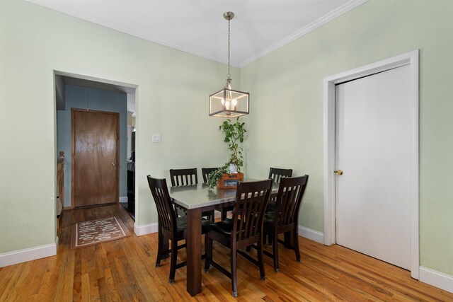 dining space featuring wood finished floors, crown molding, a chandelier, and baseboards