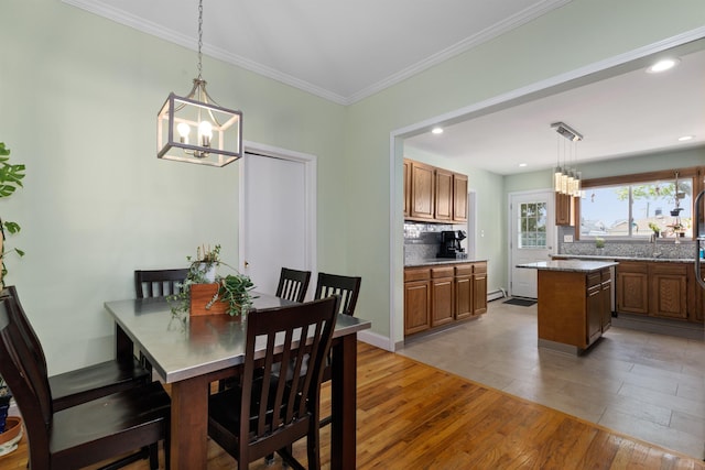 dining space featuring a chandelier, light wood-type flooring, crown molding, a baseboard radiator, and recessed lighting
