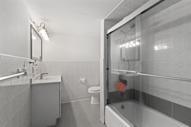 bathroom with tile walls, vanity, toilet, combined bath / shower with glass door, and tile patterned floors