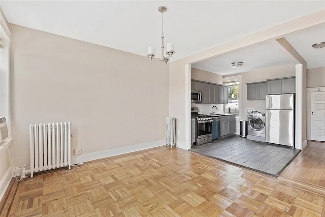 16 Belvidere Ave Unit 3F, Jersey City, NJ 07304 - kitchen featuring appliances with stainless steel finishes, radiator, a sink, gray cabinetry, and washer / dryer