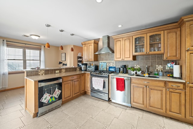 kitchen featuring pendant lighting, wall chimney range hood, sink, appliances with stainless steel finishes, and kitchen peninsula