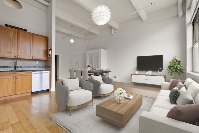 living room featuring light wood-type flooring, beamed ceiling, and a high ceiling