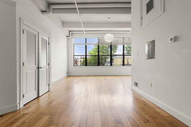interior space with electric panel, beam ceiling, baseboards, wood finished floors, and a chandelier