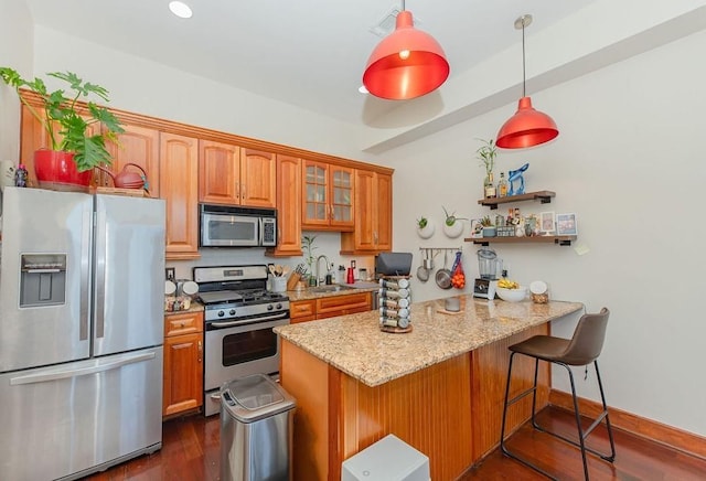 kitchen featuring dark wood-style flooring, a peninsula, a breakfast bar, a sink, and stainless steel appliances