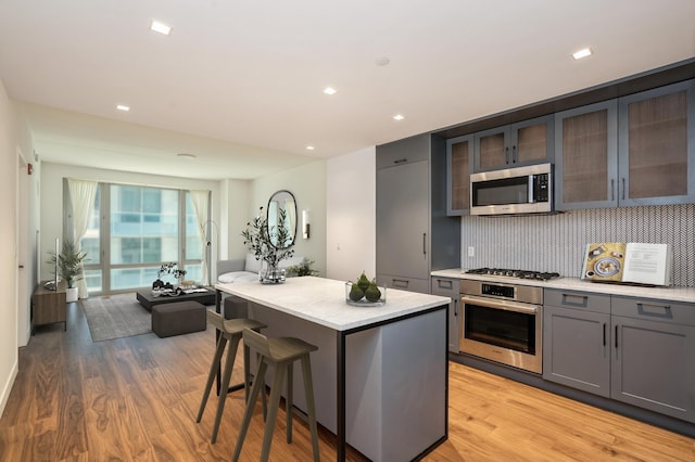 2 Shore Ln Unit 410, Jersey City, NJ 07310 - kitchen featuring stainless steel appliances, light wood finished floors, gray cabinetry, decorative backsplash, and recessed lighting