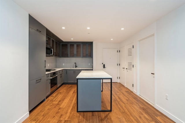 2 Shore Ln Unit 410, Jersey City, NJ 07310 - kitchen featuring appliances with stainless steel finishes, light countertops, light wood-style floors, decorative backsplash, and a center island