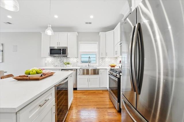 41 Graham St Unit 2, Jersey City, NJ 07307 - kitchen with stainless steel appliances, wine cooler, a sink, ornamental molding, and light wood-style flooring