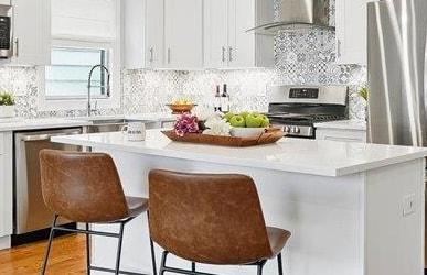 41 Graham St Unit 2, Jersey City, NJ 07307 - kitchen featuring appliances with stainless steel finishes, wall chimney exhaust hood, a breakfast bar, white cabinets, and a kitchen island