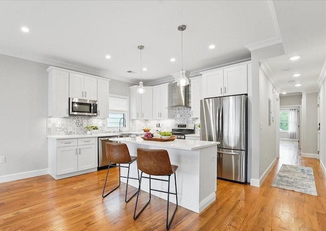 41 Graham St Unit 2, Jersey City, NJ 07307 - kitchen featuring appliances with stainless steel finishes, crown molding, wall chimney range hood, a kitchen island, and white cabinetry