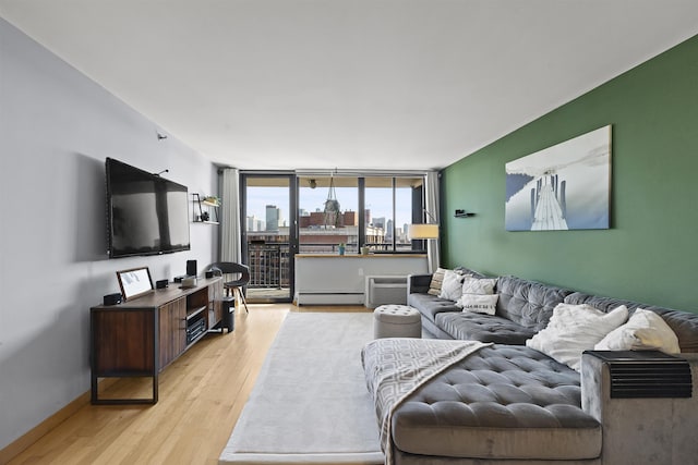 living area featuring light wood-style floors, baseboards, baseboard heating, and a wall mounted AC