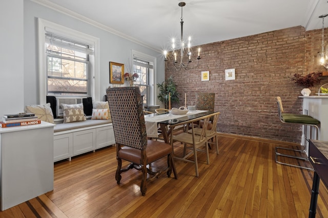 dining room featuring ornamental molding, a notable chandelier, brick wall, and wood-type flooring