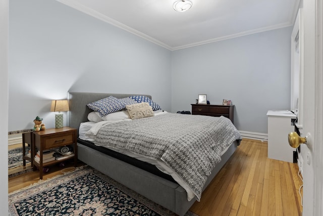 bedroom featuring baseboards, wood-type flooring, and crown molding