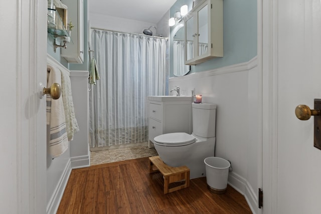 bathroom featuring toilet, a shower with shower curtain, wood finished floors, and vanity