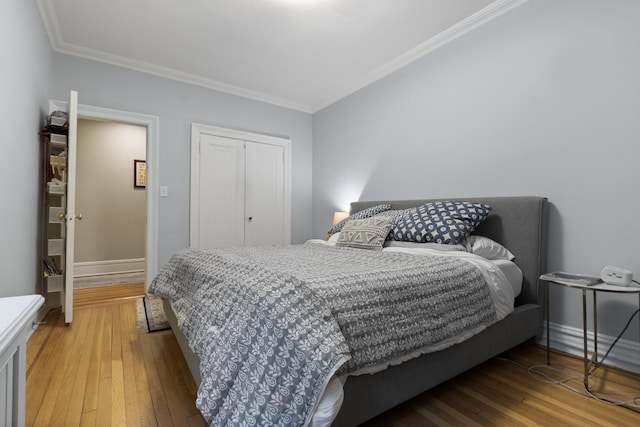 bedroom featuring crown molding, light wood-style flooring, a closet, and baseboards