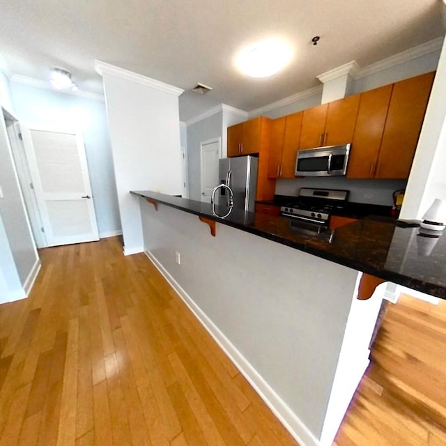 172 Culver Ave Unit 301, Jersey City, NJ 07305 - kitchen with stainless steel appliances, a peninsula, brown cabinetry, ornamental molding, and light wood-style floors