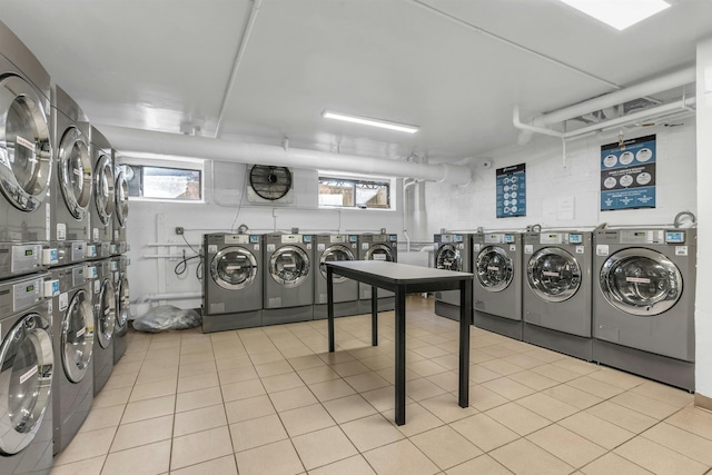 washroom with separate washer and dryer, light tile patterned floors, stacked washer and dryer, and a healthy amount of sunlight