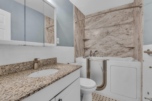 full bathroom featuring washer / clothes dryer, toilet, vanity, and tile walls