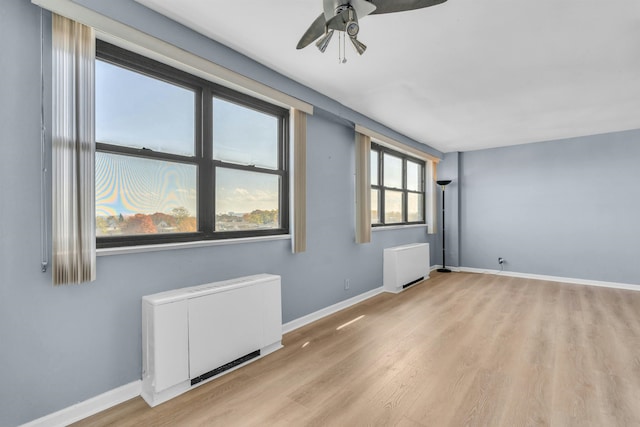 unfurnished room with ceiling fan, radiator heating unit, and light hardwood / wood-style flooring