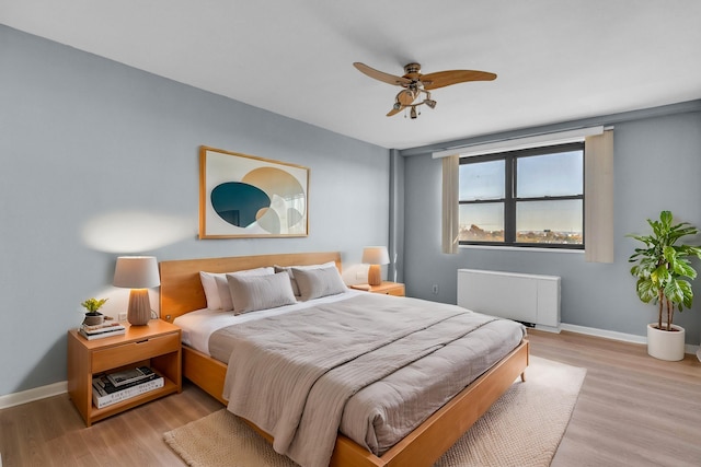 bedroom with ceiling fan, radiator, and light wood-type flooring