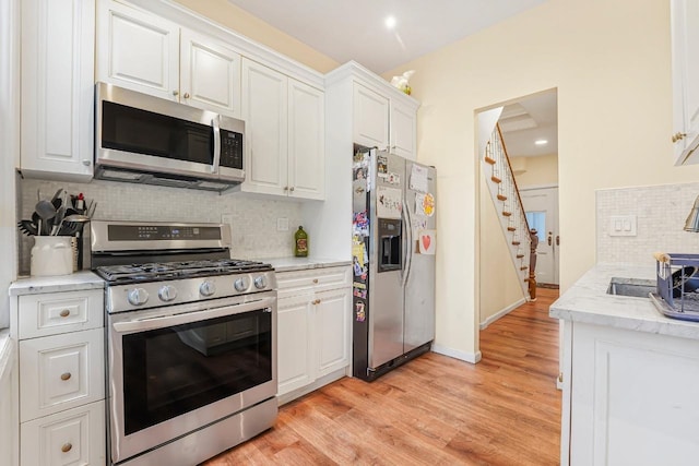 1527 38th St, North Bergen, NJ 07047 - kitchen with stainless steel appliances, white cabinetry, decorative backsplash, and light wood-style flooring