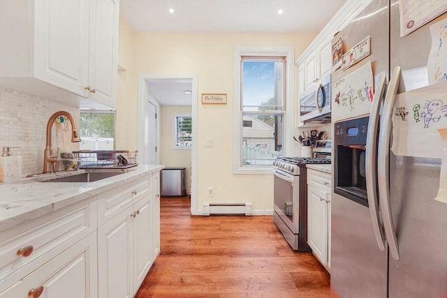1527 38th St, North Bergen, NJ 07047 - kitchen featuring stainless steel appliances, a baseboard heating unit, a sink, white cabinets, and tasteful backsplash