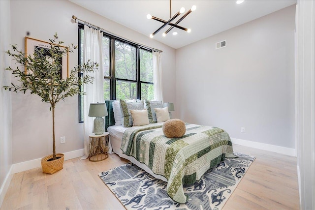 bedroom featuring an inviting chandelier, light wood-style flooring, baseboards, and visible vents