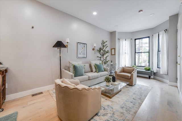 living area featuring baseboards, visible vents, and light wood-type flooring