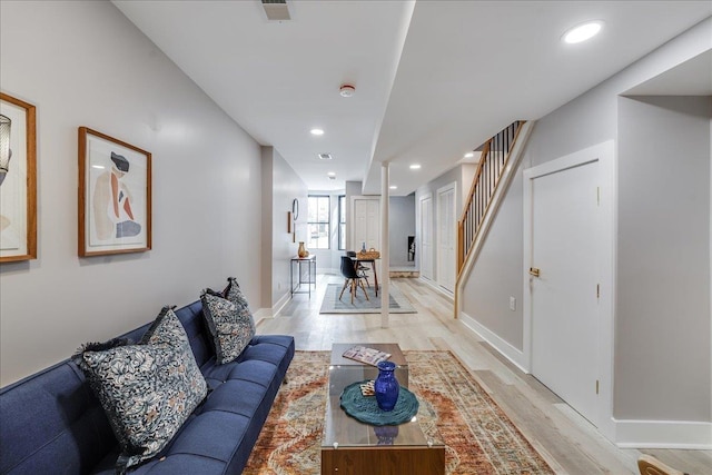 living room featuring recessed lighting, visible vents, light wood-style floors, and stairs