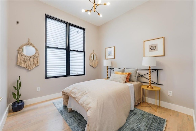 bedroom with an inviting chandelier, light wood-style flooring, and baseboards