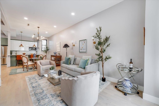 living area with a chandelier, recessed lighting, light wood-style flooring, and baseboards