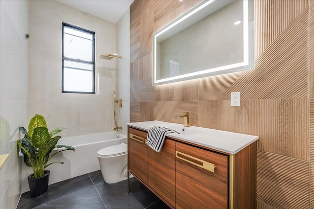 bathroom with tile patterned floors, toilet, shower / tub combination, tile walls, and vanity