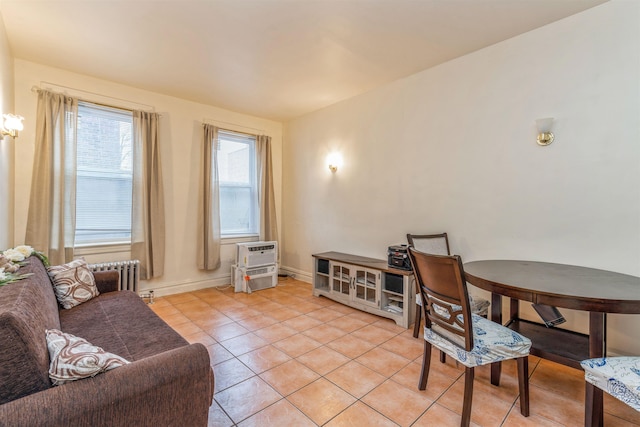 living room featuring radiator, light tile patterned floors, and a wall unit AC