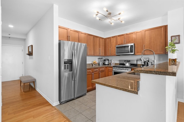 4 Constellation Pl Unit 401, Jersey City, NJ 07305 - kitchen with stainless steel appliances, brown cabinets, a chandelier, a peninsula, and a sink
