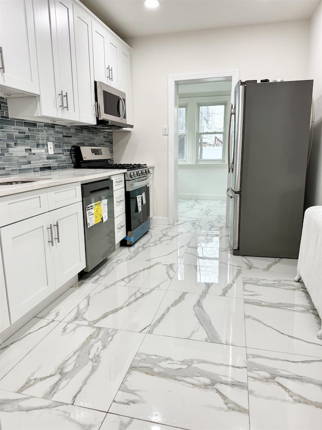 kitchen with recessed lighting, white cabinetry, marble finish floor, appliances with stainless steel finishes, and backsplash