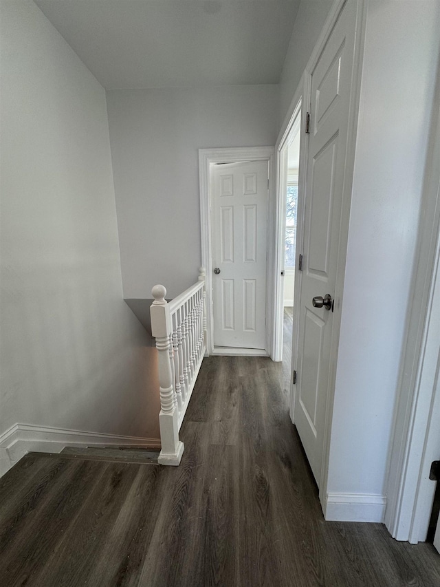 corridor featuring an upstairs landing, baseboards, and wood finished floors