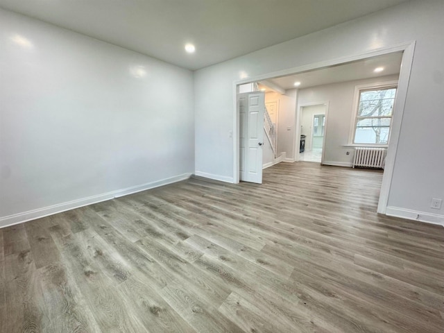 spare room featuring recessed lighting, baseboards, radiator heating unit, and wood finished floors