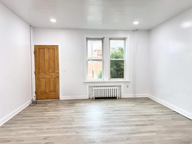 spare room with light wood-style flooring, radiator heating unit, recessed lighting, and baseboards