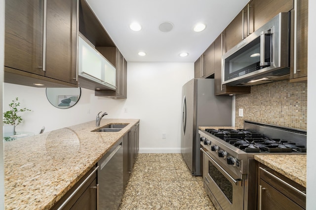 kitchen with light stone counters, appliances with stainless steel finishes, sink, and decorative backsplash