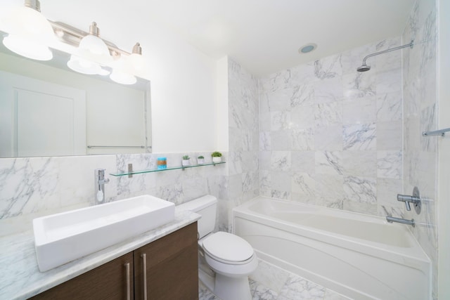 full bathroom with tiled shower / bath, tile walls, vanity, and toilet