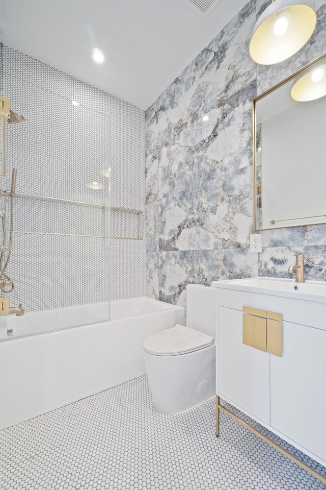 full bathroom with washtub / shower combination, tile patterned flooring, tile walls, vanity, and toilet