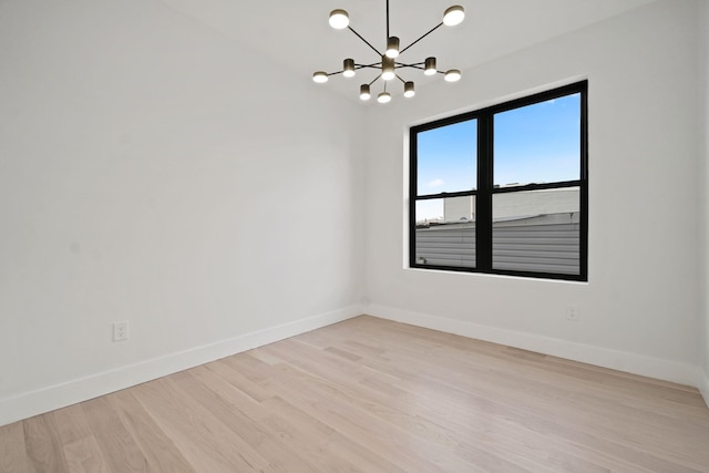 spare room with light hardwood / wood-style floors and a notable chandelier