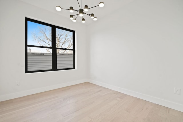 spare room with an inviting chandelier and light wood-type flooring