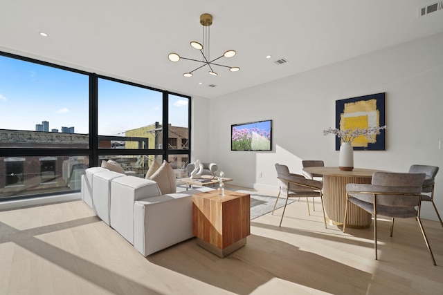 living room featuring floor to ceiling windows, a notable chandelier, and light hardwood / wood-style floors