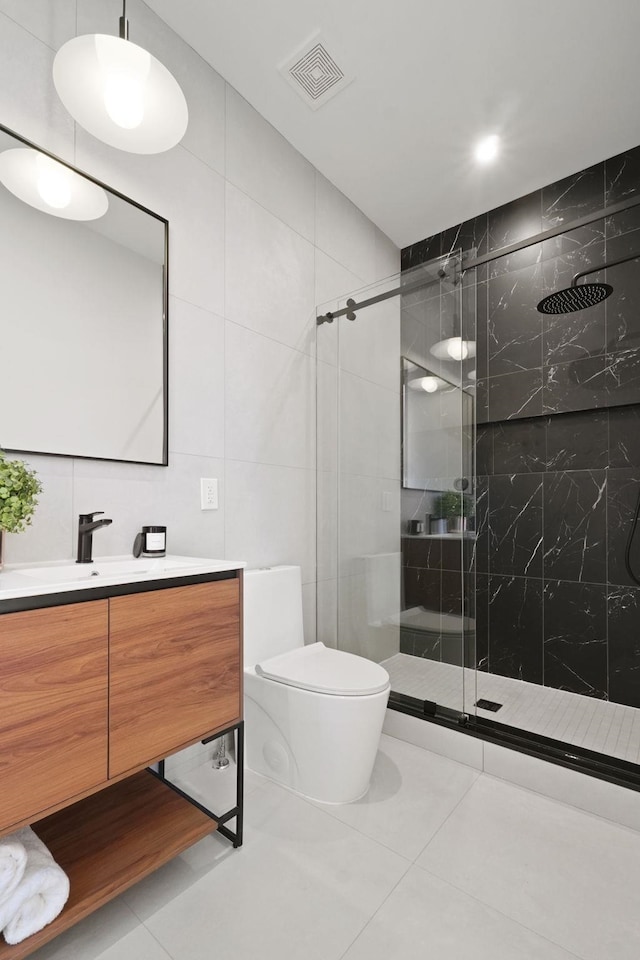 bathroom featuring tile patterned floors, toilet, a shower with door, and tile walls