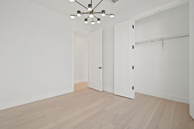 unfurnished bedroom featuring a notable chandelier, light hardwood / wood-style flooring, and a closet