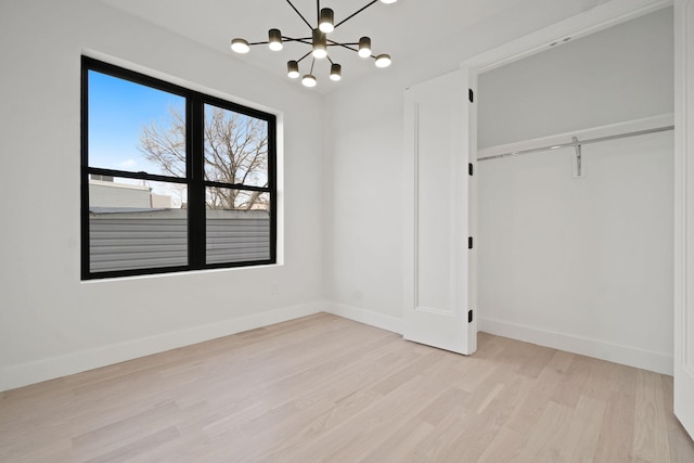 unfurnished bedroom featuring a chandelier, a closet, and light wood-type flooring