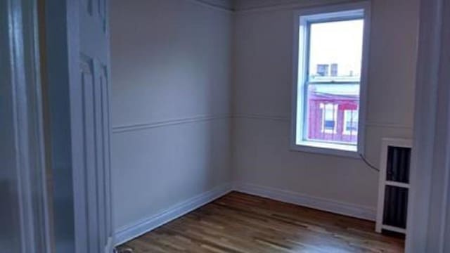 spare room featuring plenty of natural light, dark wood finished floors, and baseboards