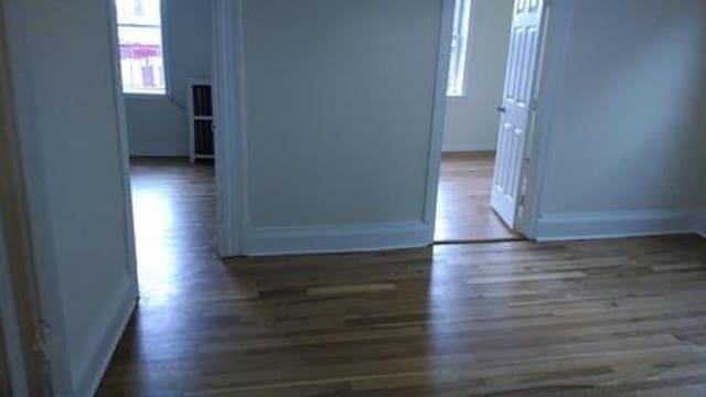 hallway featuring wood finished floors and baseboards