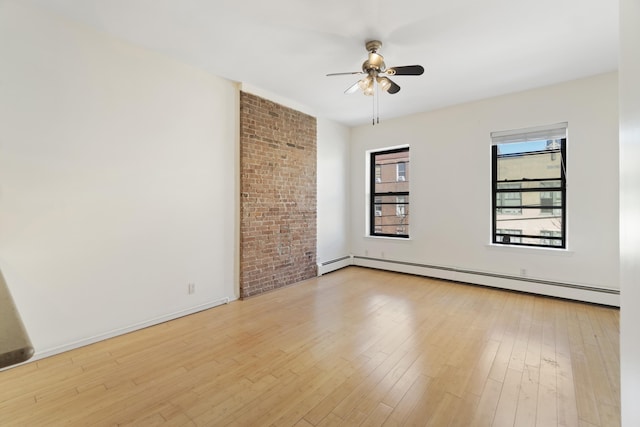 empty room featuring a baseboard heating unit, light wood-style floors, baseboards, and a ceiling fan